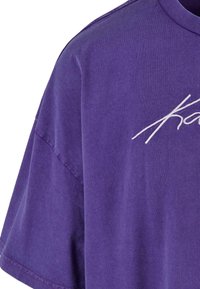 Lila bomulls t-shirt med rund halsringning, korta ärmar och broderad vit textdetalj. Mjuk textur med avslappnad passform.