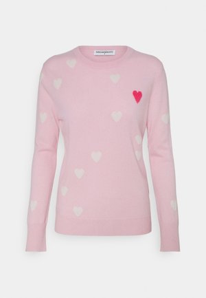Pull rose clair à manches longues, décoré de petits cœurs blancs et d'un cœur rouge proéminent sur la poitrine gauche.