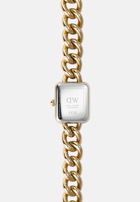 Montre en métal doré avec un bracelet en chaîne épaisse, dotée d'un cadran rectangulaire en acier inoxydable argenté au design minimaliste et d'une gravure au dos.