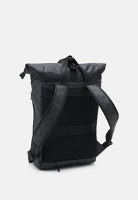 Zaino roll-top nero realizzato in materiale resistente, dotato di pannello posteriore in rete, spallacci regolabili e un motivo discreto sui lati.
