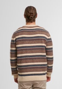 Maglione a maglia con un motivo a righe nei toni del beige, marrone e blu scuro. Il tessuto testurizzato presenta un orlo e polsini a coste.