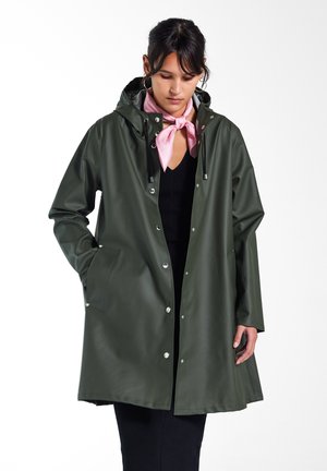 Grønn vanntett jakke med hette, frontsnap-lukking og sidelommer. Glatt tekstur, litt oversized passform og matchende rosa skjerf.