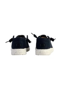 Sneaker in tessuto blu navy con fiocchi decorativi sul retro, suole bianche macchiate e marchio ben visibile sul tallone.