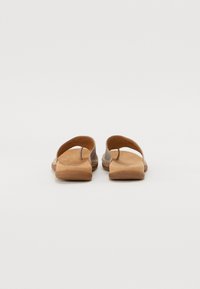 Sandali in cuoio marrone con suola piatta, schiena aperta e doppie cinghie. Texture morbida, design minimalista, adatti per un abbigliamento casual.
