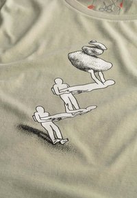 Beige katoenen T-shirt met een grafiek van twee vereenvoudigde figuren die een derde figuur dragen in de vorm van opgestapelde stenen, met subtiele textuur.