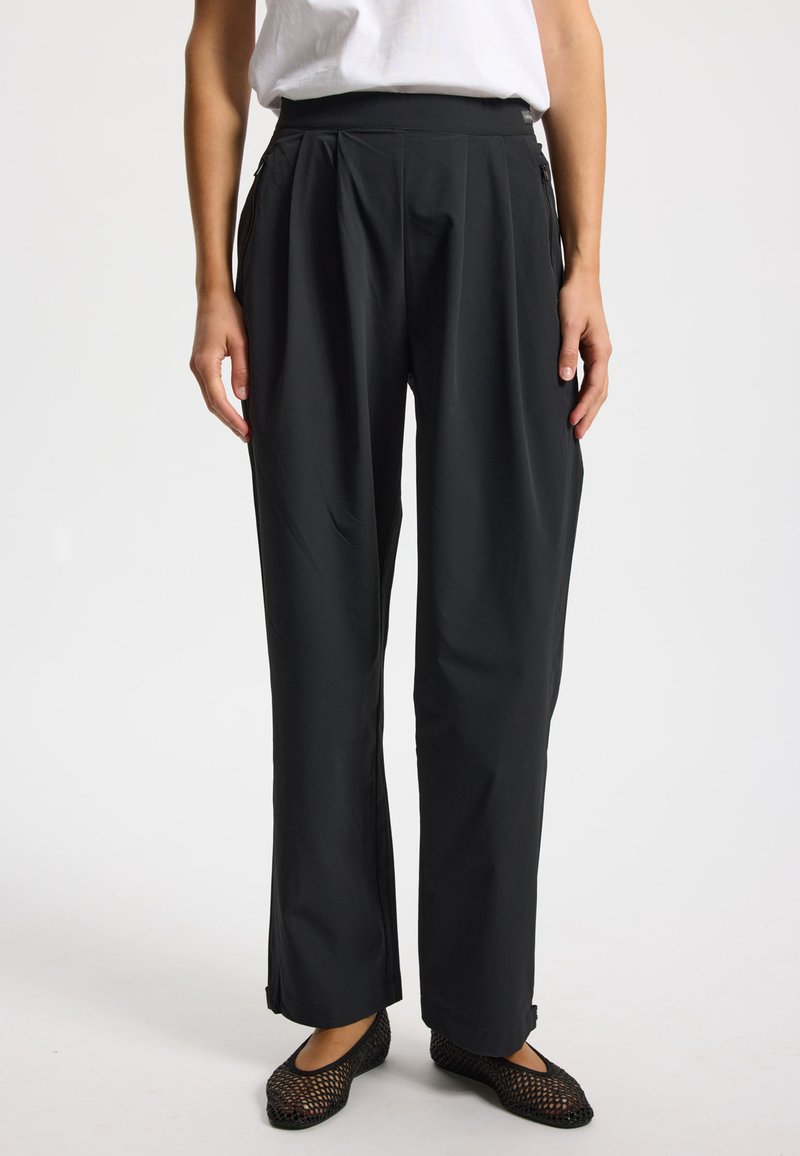 Čierne plisované nohavice s vysokým pásom, vybavené bočnými vreckami so zipsom a hladkou, ľahkou tkaninou. Rovný strih nohavíc.