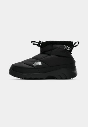 Black insulated ankle boot with adjustable drawstring top, thick textured sole, and white “The North Face” and "700" logos on side and heel.