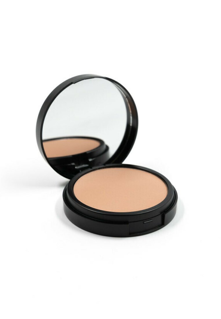 Cipria compatta rotonda con superficie liscia di un beige chiaro, racchiusa in un involucro di plastica nera con uno specchio all'interno.
