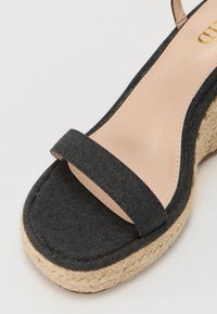 Mustmust mustkanna laia rihmaga, beež juba ja kootud jute tallaga. Tekstuuriga pealmine osa ja sile nahast detail.