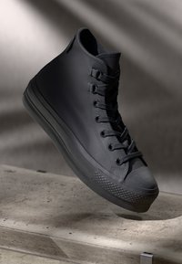 Baskets montantes noires en cuir texturé, avec un design à lacets, un capuchon en caoutchouc à l'avant et un motif de semelle distinctif.