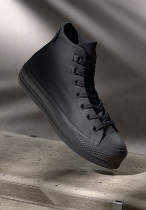 Baskets montantes noires en cuir texturé, avec un design à lacets, un capuchon en caoutchouc à l'avant et un motif de semelle distinctif.