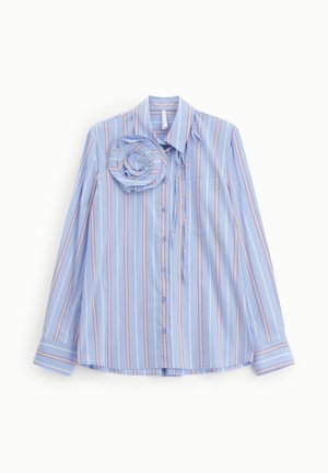 Blusa azzurro chiaro a maniche lunghe con strisce verticali bianche e rosse, chiusura frontale con bottoni, collo e un grande dettaglio floreale in stoffa vicino alla spalla.