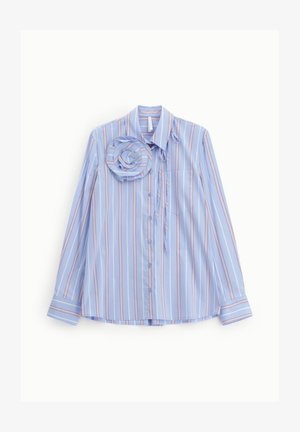 Blusa azzurro chiaro a maniche lunghe con strisce verticali bianche e rosse, chiusura frontale con bottoni, collo e un grande dettaglio floreale in stoffa vicino alla spalla.