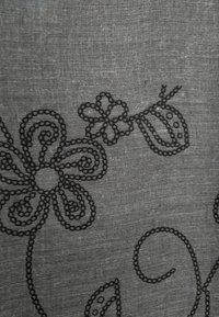 Zwarte geborduurde bloemen- en bladmotieven op een grijze stofachtergrond, met gebogen lijnen en cirkelvormige details.