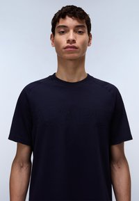 Navy blue t-shirt made from cotton, featuring a round neck, short sleeves, and raised stitching that spells "PAPAJ." Smooth texture.