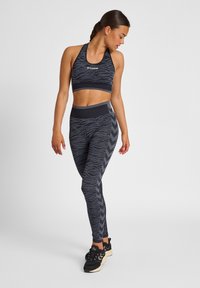 Svart sport-bh och leggings-set med zebramönster och chevron-detaljer. Tillverkad av stretchy material för komfort och rörlighet under träning.