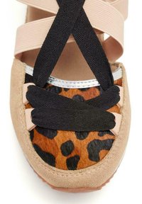 Ballerine con stampa leopardata e punta in suede color tan. Presenta cinturini incrociati elastici neri e finiture metalliche attorno al bordo. Texture morbida.