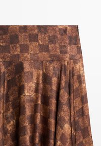 Jupes à carreaux marron avec une texture lisse, présentant une taille haute et un design plissé. Le motif est constitué de carrés clairs et foncés alternés.