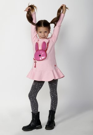 Roze languit jurk met een uitlopende zoom en een tas in de vorm van een konijn met pailletten. Grijze leggings met een luipaardpatroon. Zwarte combatlaarzen.