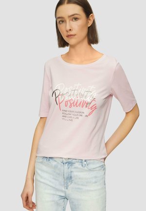 T-shirt en coton rose clair avec un col rond, des manches courtes et un imprimé graphique indiquant "Positivité" dans différentes teintes et styles.