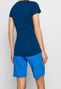 Camiseta azul marino hecha de tela suave con mangas cortas, combinada con pantalones cortos azul brillante que cuentan con una cinturilla elástica y textura lisa.