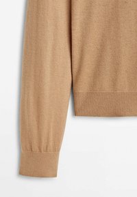 Pull beige à manches longues avec poignets et ourlet côtelés sur fond blanc.