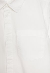 Hvid skjorte med krave lavet af bomuld, med knappelukning foran, en enkelt brystlomme og flade sømme for et rent finish.