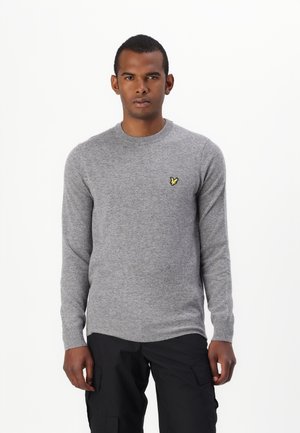 Pull en tricot gris avec des manches longues et un col rond. Présente un petit logo de papillon jaune sur la poitrine gauche. Texture douce.