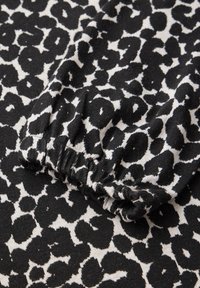 Schwarzes und weißes Leopardenmuster-Stoff mit einem elastischen Bund, der eine weiche Textur und ausgeprägte Musterelemente zeigt.