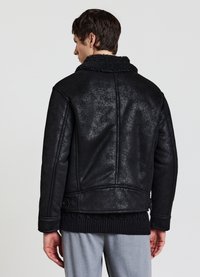 Giacca nera in ecopelle con finitura texturizzata, colletto in shearling e dettagli con bottoni. Presenta cuciture visibili e una vestibilità comoda.