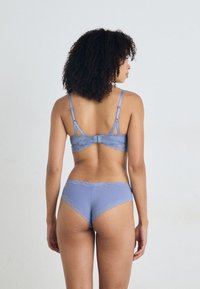 Light blue lingerie set featuring a lace-trimmed bra and matching panties, showcasing soft fabric and delicate scalloped edges.
