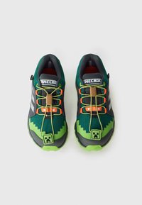 Zapatillas verdes y grises con parte superior de malla texturizada, patrón en zigzag, cordones naranjas y detalle integrado del logo de Minecraft.