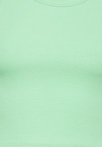 Top sin mangas de color verde menta con un escote redondeado. La textura es suave y el tejido parece elástico y ajustado.