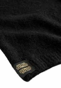 Fekete gyapjú anyag lágy tapintással, dombornyomott mintával. Tartalmaz egy fekete címkét arany díszes mintával.