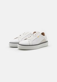 Weiße Ledersneaker mit glatter Oberfläche, Schnürdesign, gepolstertem Schaft und dezenten grauen sowie gelben Akzenten an der Seite. Flache Gummisohle.