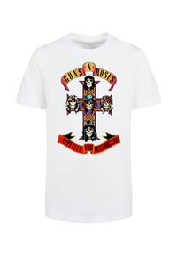 White t-shirt with a colorful cross graphic featuring five skulls with band-themed hairstyles and text "Guns N' Roses" and "Appetite for Destruction."