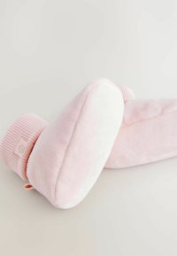 Chaussons en polaire rose avec un bord en tricot côtelé. Texture douce, forme arrondie, détail subtil d'étiquette florale. Convient pour un usage intérieur.