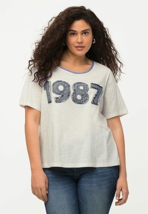 Světle šedé tričko s výraznou, texturovanou modrou džínovou aplikací s rokem "1987". Kolo krk s kontrastním modrým lemem. Krátké rukávy.