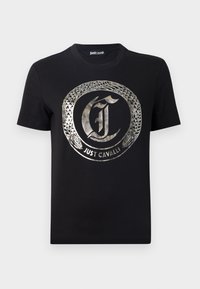 T-shirt en coton noir avec un logo métallique argenté représentant un serpent entourant les lettres "J" et "C". Manches courtes, col rond.