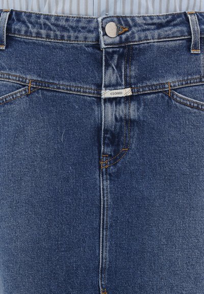 Blugi din denim albastru cu talie înaltă, cu buzunare frontale, închidere cu fermoar și accente de cusătură aurie. Eticheta spune "CLOSED" pe talie.