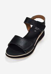 Sandalia de cuero negra con dos correas anchas, acabado texturizado, punta abierta, plantilla acolchada y una suela de color claro, ligeramente elevada.