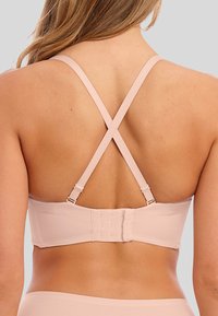 Světle růžová podprsenka s hladkým povrchem, křížovými ramínky a nastavitelným háčkovým zapínáním vzadu. Má jednoduchý design bez viditelných log. 