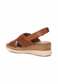 Sandali con zeppa in pelle marrone con motivo floreale ritagliato, suola interna ammortizzata e suola in gomma. Presenta una cinghia alla caviglia regolabile per una migliore vestibilità.