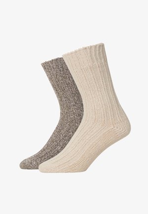 Deux paires de chaussettes côtelées : une en beige clair et l'autre en marron foncé avec un motif moucheté. Les deux ont une texture douce et tricotée.