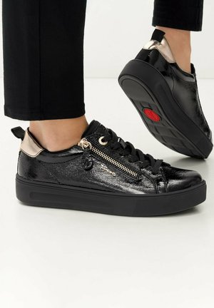 Sneakers in pelle verniciata nera con dettaglio zip dorato e superficie testurizzata, suola nera e accento metallico sul tallone.