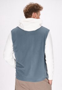 Kapuzenshirt aus weichem, hellblauem Fleece mit einer weißen Kapuze. Verfügt über ein ärmelloses Design und verstellbare Kordeln an der Kapuze.
