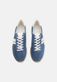 Zapatillas de ante azul con cordones blancos, parte superior texturizada, dos rayas blancas a lo largo de los lados y suela de goma.