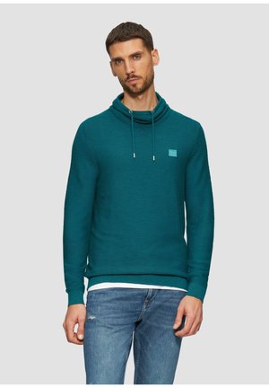 Teal hoodie met een kraag en trekkoord, gemaakt van een gestructureerde stof. Bevat een klein, lichtblauw logo-embleem op de borst. Gecombineerd met blauwe spijkerbroek.
