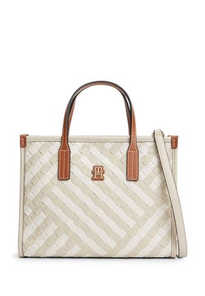 Μπεζ υφασμάτινη τσάντα ώμου με καφέ δερμάτινες λαβές, αποσπώμενο ιμάντα ώμου και μικρό μεταλλικό λογότυπο στο κέντρο μπροστά.