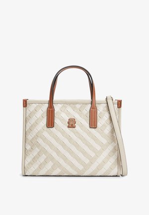 Beige woven tote bag with brown leather handles, detachable shoulder strap, and a small metallic logo on front center.